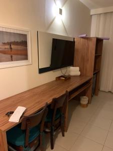 a room with a desk with a television and chairs at Pérola do Tree Bies Resort in Entre Rios
