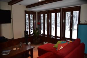PETIT COIN DE PARADIS في Sainte Anne des Lacs: غرفة معيشة مع أريكة حمراء وبعض النوافذ