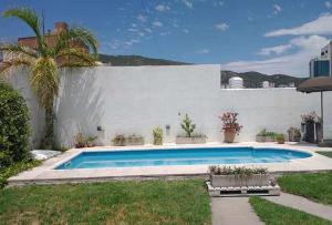 a swimming pool in a yard next to a white wall at Casa Carlos Paz in Villa Carlos Paz