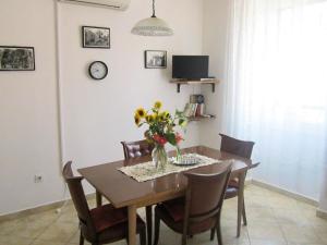 una mesa de comedor con sillas y un jarrón de flores en Apartments by the sea Komiza, Vis - 8533, en Komiža