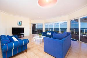 a living room with blue couches and a television at Palm Road in Forster