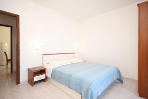 a white bedroom with a bed and a night stand at Apartments with a parking space Rukavac, Vis - 8849 in Vis