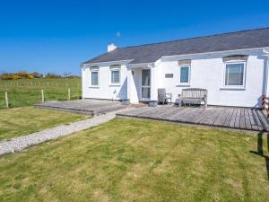 a white house with a wooden deck in the yard at Happy Daze in Pwllheli