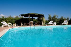 a swimming pool with chairs and a gazebo at Agriturismo De Santis in Castiglioncello