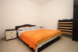 a bedroom with a bed with an orange blanket at Apartments by the sea Necujam, Solta - 8647 in Grohote