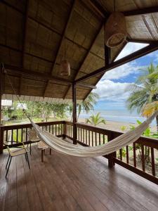 a hammock on a porch with a view of the beach at Irana Pacific Hotel in Nuquí