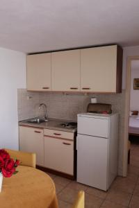 a kitchen with white cabinets and a white refrigerator at Apartments and rooms by the sea Komiza, Vis - 8841 in Komiža