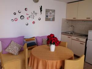 a kitchen with a table with a vase of flowers on it at Apartments and rooms by the sea Komiza, Vis - 8841 in Komiža