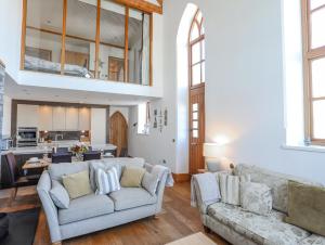 a living room with two couches and a kitchen at Capel Tabernacl in Pwllheli