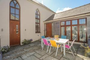 a patio with a white table and colorful chairs at Capel Tabernacl in Pwllheli