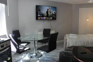 uma sala de estar com uma mesa de vidro e cadeiras em Cosy Central Luton Studio Flat -Ideal for Airport! em Luton