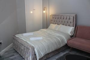 uma cama com duas toalhas ao lado de uma cadeira em Cosy Central Luton Studio Flat -Ideal for Airport! em Luton