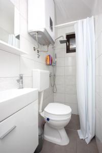 a white bathroom with a toilet and a sink at Apartments by the sea Rogac, Solta - 8688 in Grohote