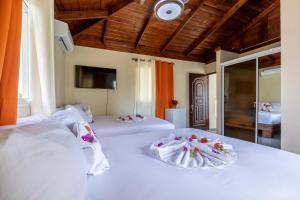 a bedroom with two beds with white sheets and flowers on them at Hotel Turístico Marian in Las Terrenas