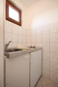 a white tiled kitchen with a sink and a window at Apartments with a parking space Rukavac, Vis - 8863 in Rukavac
