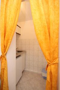 a bathroom with a yellow curtain in a kitchen at Studio Rukavac 8863a in Rukavac