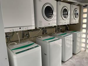 four washing machines are lined up in a laundry room at Holiday Homes TSUBOYA 301 in Naha