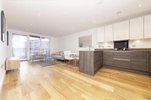 a kitchen with white cabinets and a wooden floor at Stylish family sized 2 bedroom apartment in London