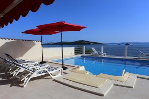 basen z krzesłami i czerwonym parasolem w obiekcie Seaside family friendly house with a swimming pool Seget Vranjica, Trogir - 10336 w mieście Seget Vranjica