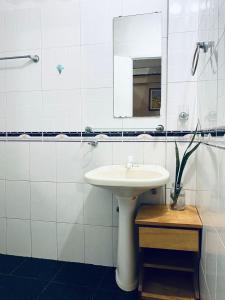 a white bathroom with a sink and a mirror at Cayetana in Puerto Iguazú