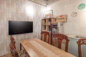 a kitchen with a table and two chairs and a television at 紫品花筑Purple Flower House in Anping