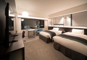 Hotel Vischio Osaka-JR Hotel Group في أوساكا: غرفة فندقية بسريرين ومكتب