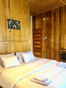een groot bed in een kamer met houten wanden bij stay KULTURA in Banda Aceh