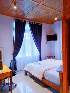 een slaapkamer met een bed, een bureau en een raam bij stay KULTURA in Banda Aceh