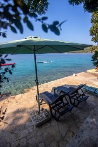 a pair of chairs under an umbrella next to the water at Apartments by the sea Necujam, Solta - 11090 in Grohote