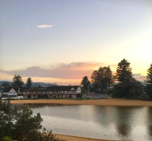 a sunset over a lake in front of a building at The Clan Terrigal in Terrigal