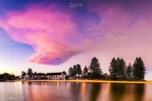 a cloudy sky over a lake with trees and houses at The Clan Terrigal in Terrigal