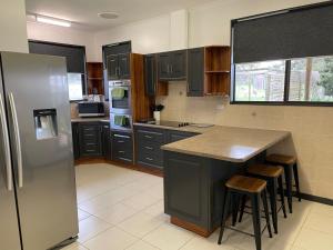 a kitchen with a refrigerator and a counter with stools at Heartland Hideaway in Vivonne Bay