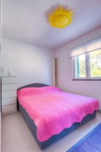 1 dormitorio con cama rosa y ventana en Apartments by the sea Rogac, Solta - 11220 en Rogač