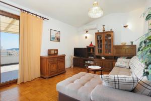 Apartments with a parking space Seget Vranjica, Trogir - 11273 في تروغير: غرفة معيشة مع أريكة وتلفزيون