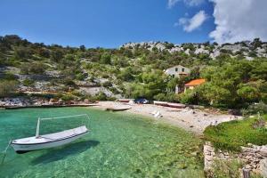 łódź siedząca w wodzie na plaży w obiekcie Apartments by the sea Sevid, Trogir - 11529 w mieście Sevid