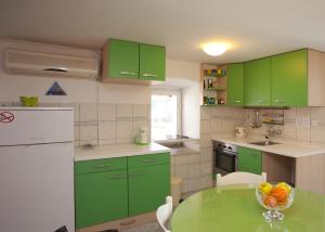 a kitchen with green cabinets and a table with a bowl of fruit at Apartments by the sea Split - 11161 in Split