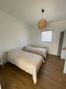2 Betten in einem weißen Zimmer mit Fenster in der Unterkunft La Baronnière de Loctudy in Loctudy
