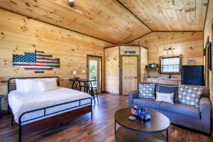 ein Schlafzimmer in einem Blockhaus mit einem Bett und einem Sofa in der Unterkunft Patriots Tiny Home w Hot Tub Fire Pit Grill in Sevierville