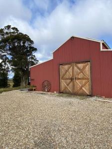 a red barn with two wooden doors and a tree at Farm Stay Unique Barn in Southern Highlands in Joadja Creek
