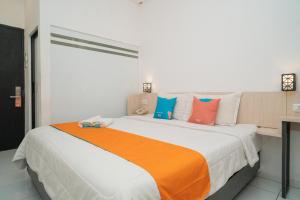 a bedroom with a large bed with colorful pillows at Sans Hotel Fif Fa Premiere Malang by RedDoorz in Malang