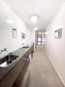 a bathroom with two sinks and a long hallway at Franz Josef TOP 10 Holiday Park in Franz Josef