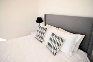 1 cama blanca con 2 almohadas blancas y negras en Luxury Modern Farm Stay Home in Southern Highlands en Joadja Creek