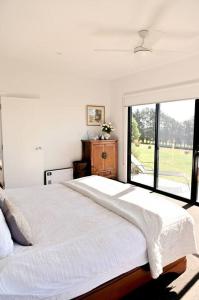 1 dormitorio con 1 cama grande y ventana grande en Luxury Modern Farm Stay Home in Southern Highlands en Joadja Creek