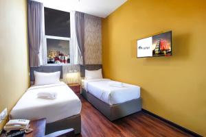 a room with two beds and a tv on the wall at CitiVilla Penang in George Town