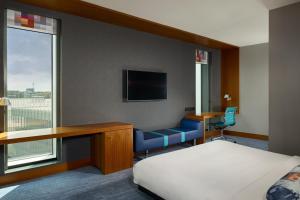 a hotel room with a bed and a desk and a tv at Aloft London Excel in London