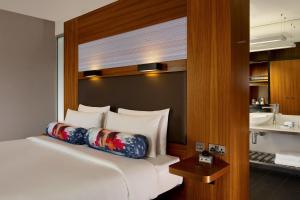 a bedroom with a white bed with a wooden headboard at Aloft London Excel in London