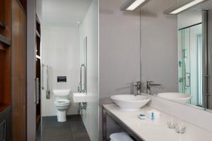 a bathroom with two sinks and a toilet at Aloft London Excel in London