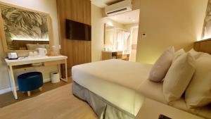Harolds Evotel Quezon City في مانيلا: غرفة الفندق بسرير كبير ومكتب