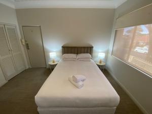 ウーロンゴンにあるNormandie Wollongongのベッドルーム(白い大型ベッド、ランプ2つ付)