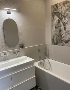 W łazience znajduje się umywalka, wanna i lustro. w obiekcie Appartement Le Palais du Commerce w mieście Vichy